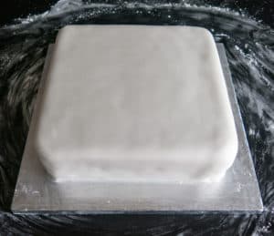 Gluten free, vegan Christmas cake with icing layer placed on top. Shaped around cake. Ready for drying out or decorating